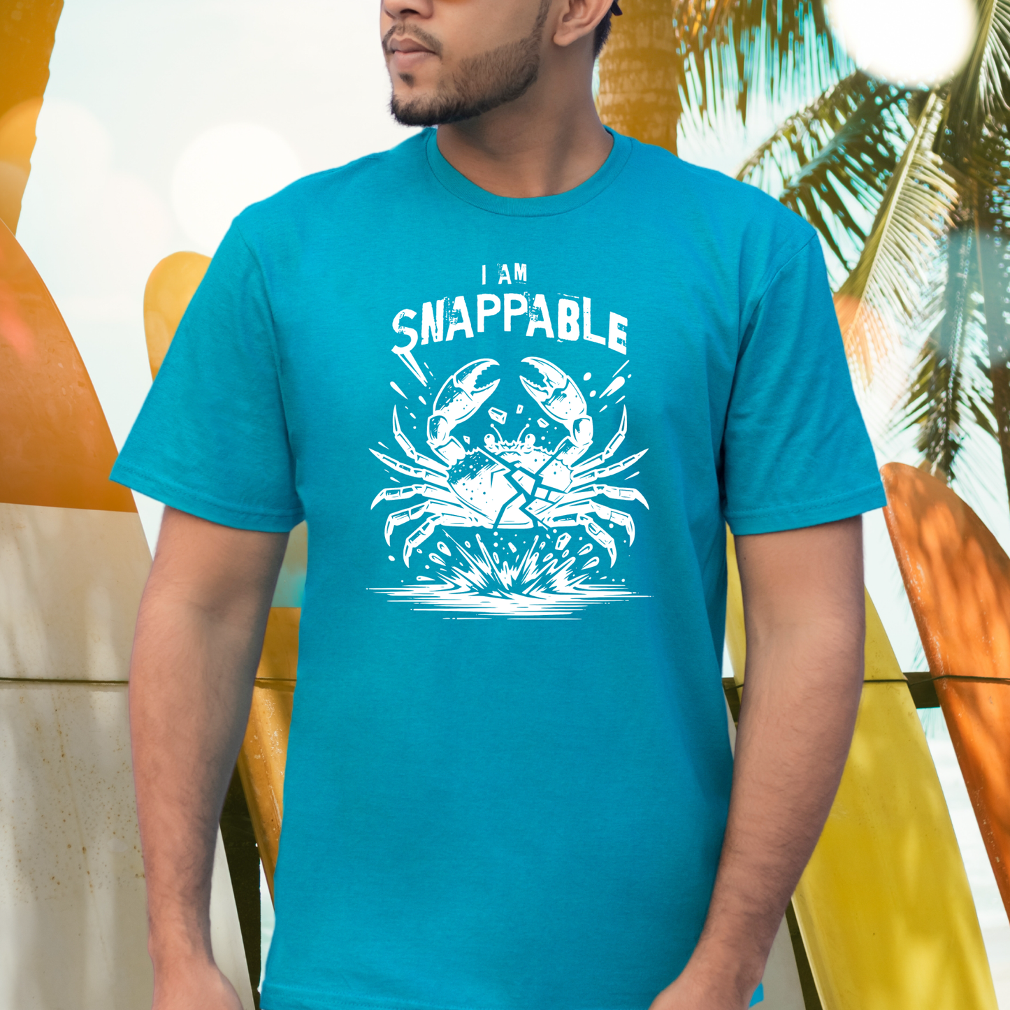 Gildan 5000 "I Am Snappable" t shirt with a crab cracked in half in a one color graphic. Picture of a man standing by surfboards wearing a t shirt.