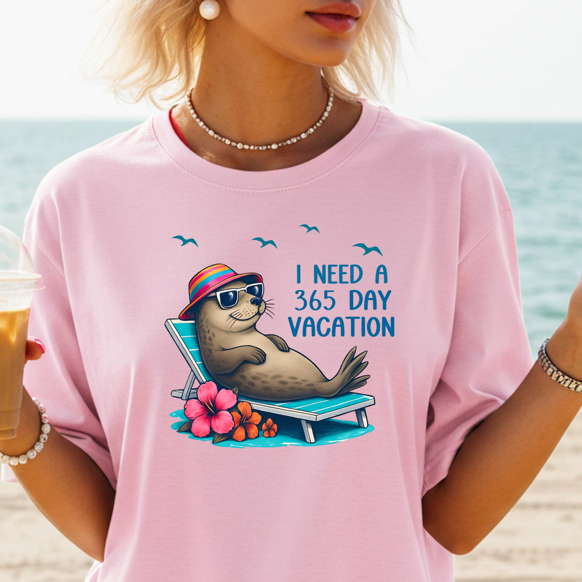 Person wearing a pink t-shirt with a seal graphic and text on a beach.