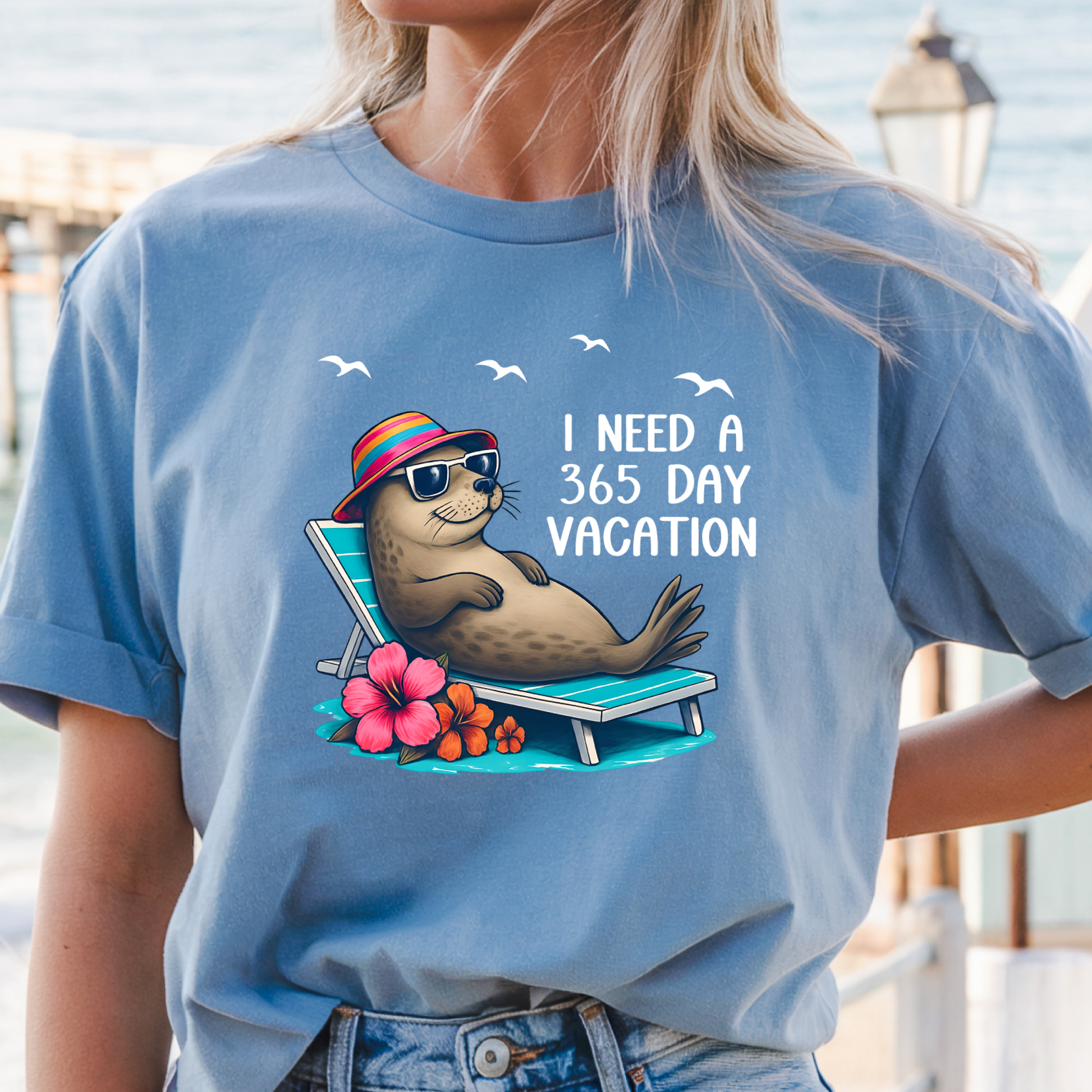 Person wearing a Carolina blue t-shirt with a seal graphic and text by a waterfront.