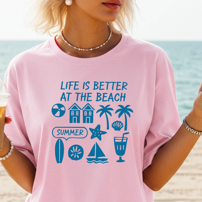 Person wearing a pink t-shirt with beach-themed graphics and text at the beach.