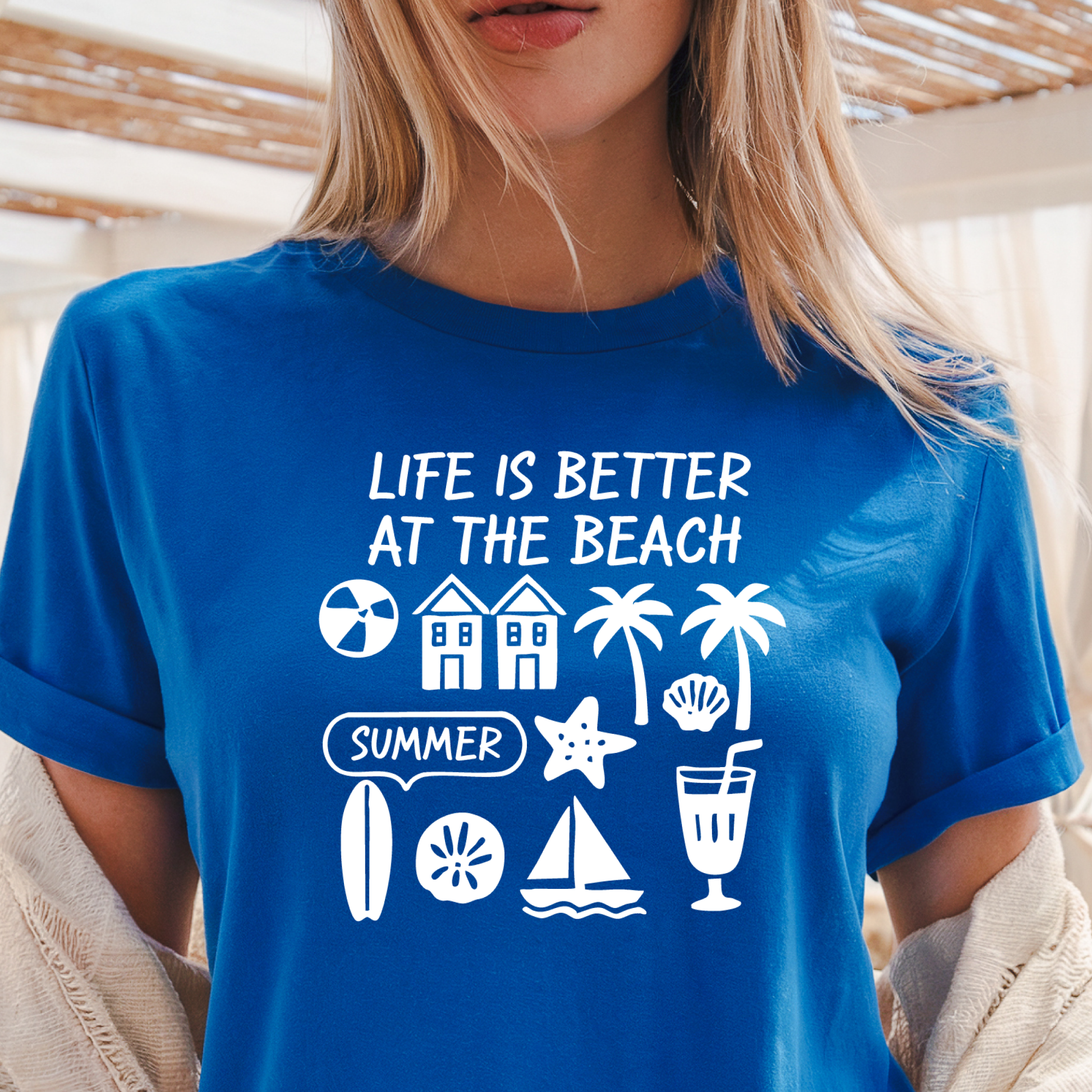 Person wearing a royal blue t-shirt with beach-themed graphics and text.