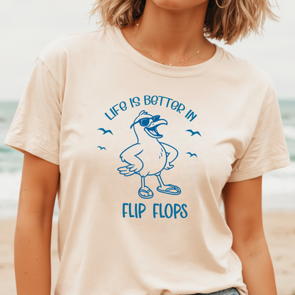 Person wearing a beige t-shirt with a blue seagull graphic and text on a beach.