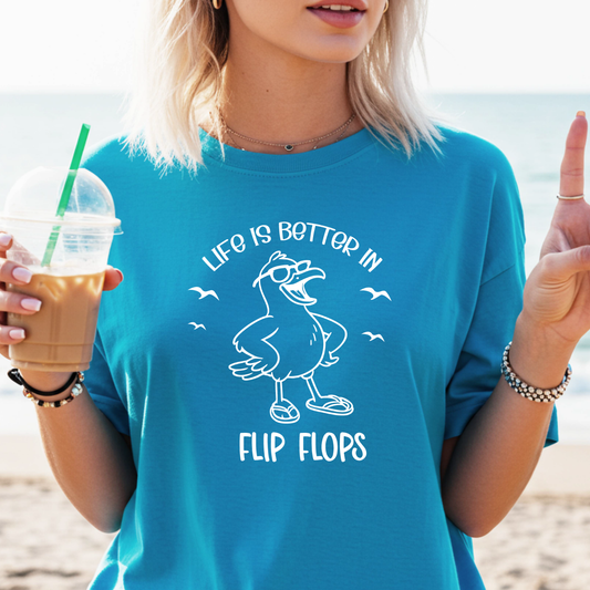 Person wearing a sapphire blue t-shirt with a duck graphic and text on a beach.