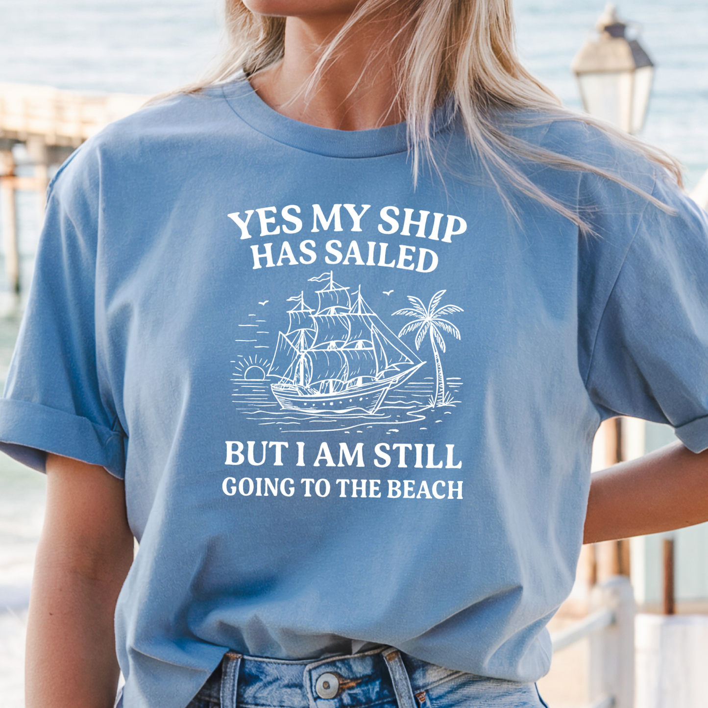 Person wearing a Carolina blue t-shirt with a ship and beach graphic and text.