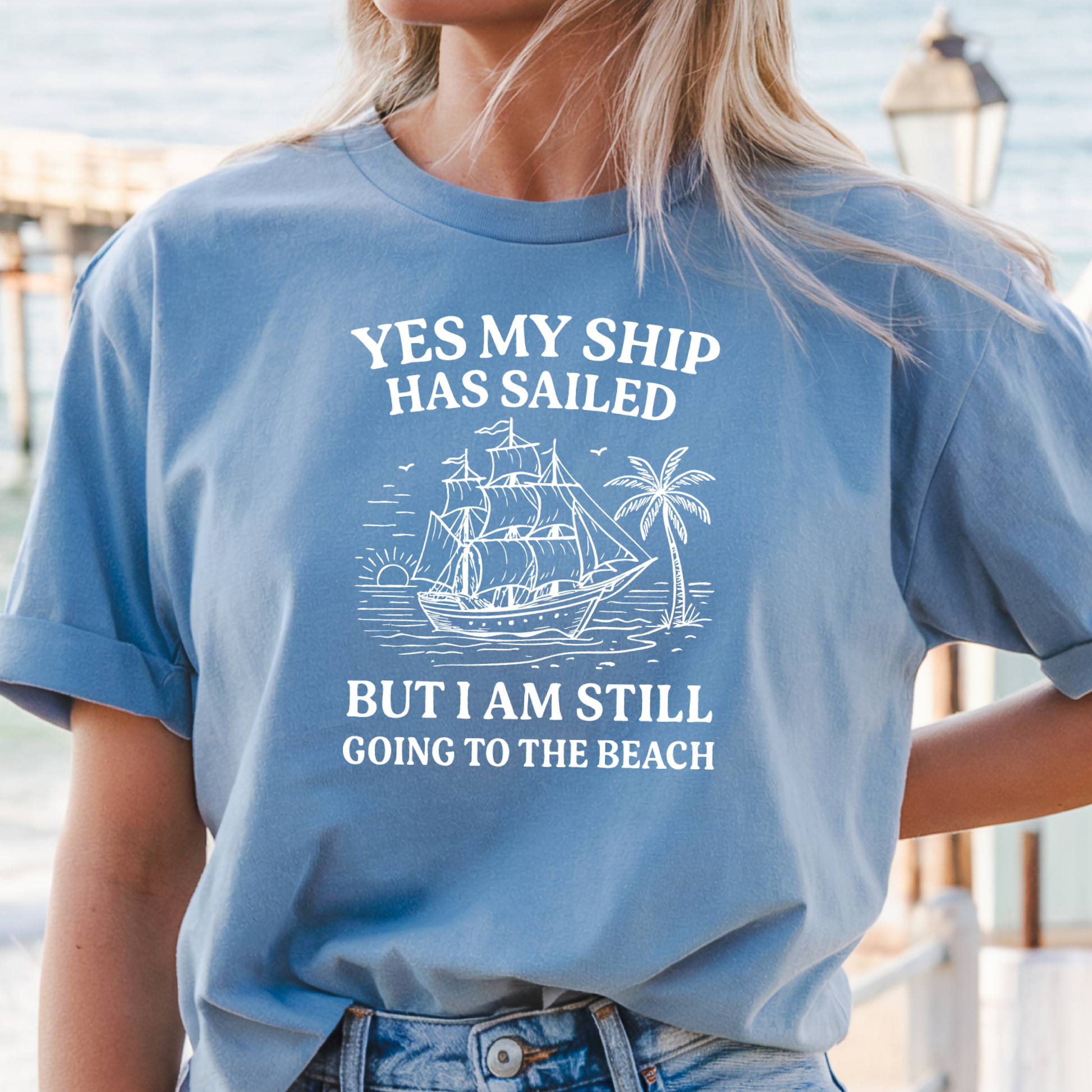 Person wearing a Carolina blue t-shirt with a ship and beach graphic and text.