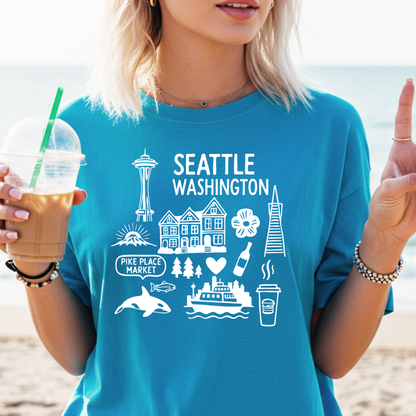 Person wearing a blue t-shirt with Seattle-themed graphics on a beach.