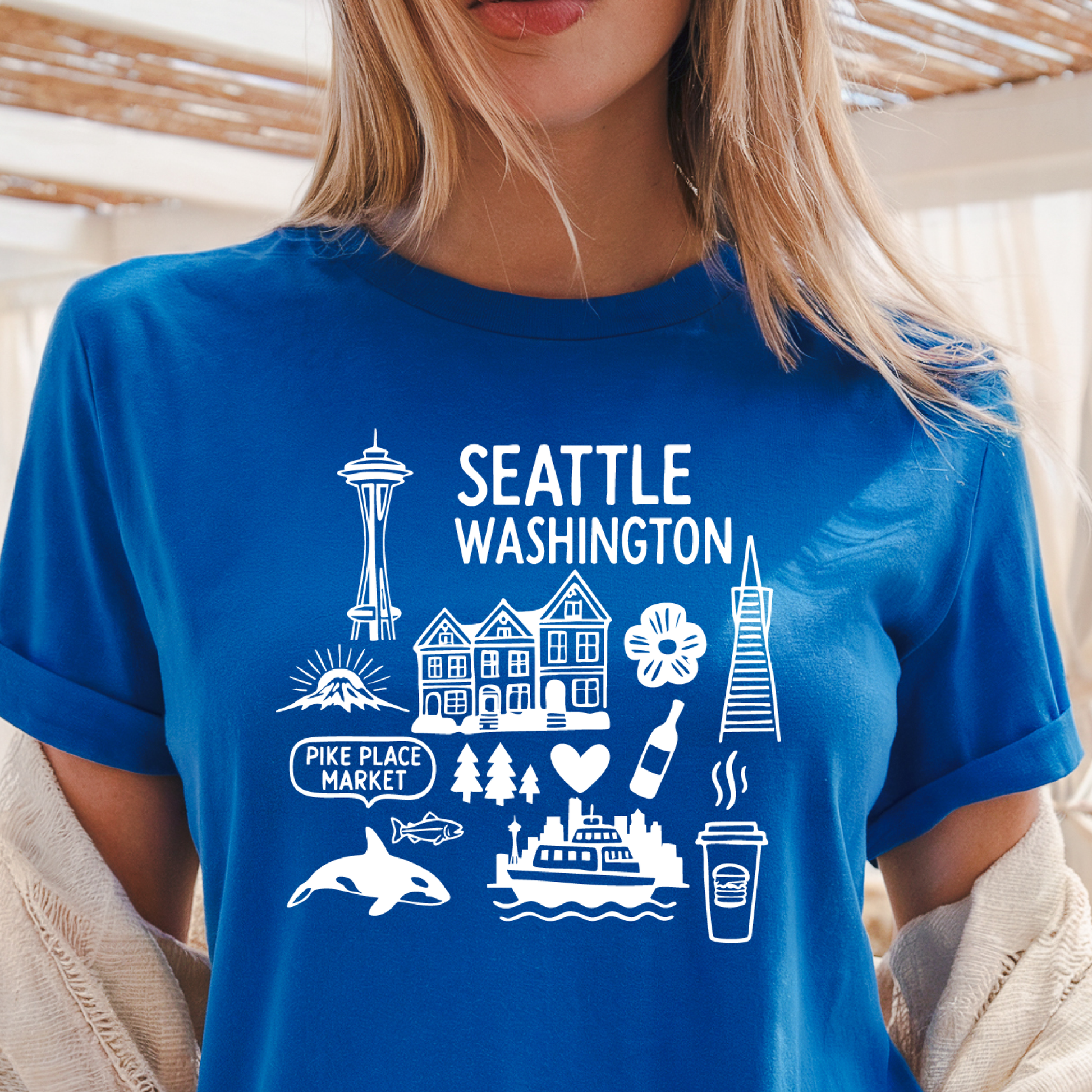 Person wearing a blue t-shirt with Seattle-themed graphics