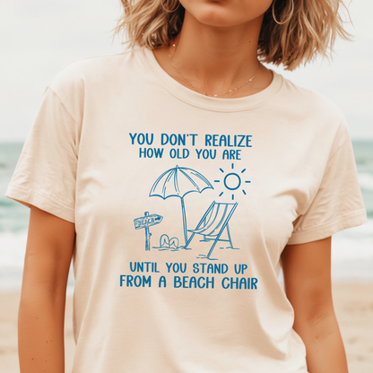 Person wearing a t-shirt with a beach-themed design and text on a beach background