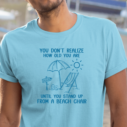 Person wearing a light blue t-shirt with a beach-themed graphic and text.