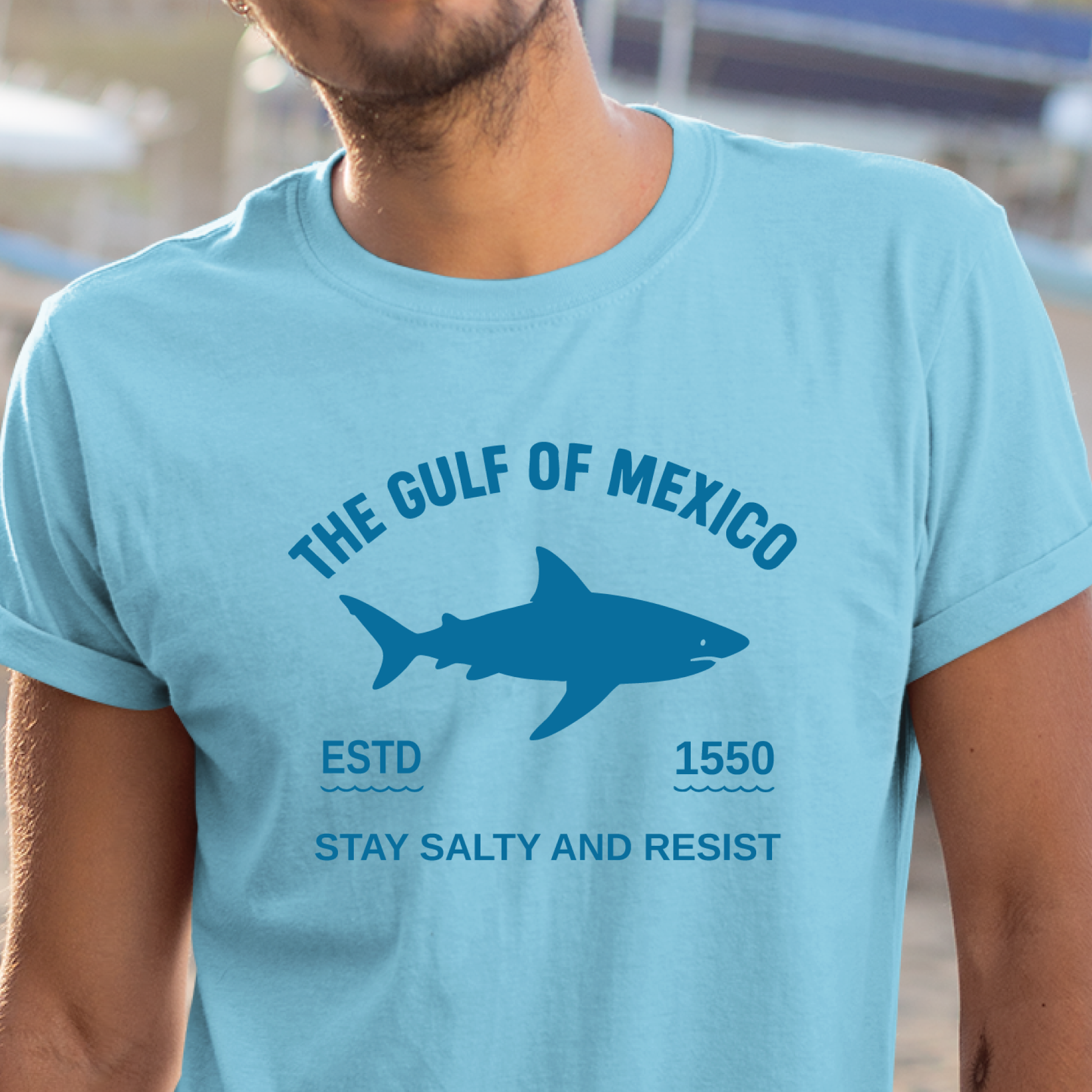 Sky blue t-shirt with shark graphic and text on a blurred background