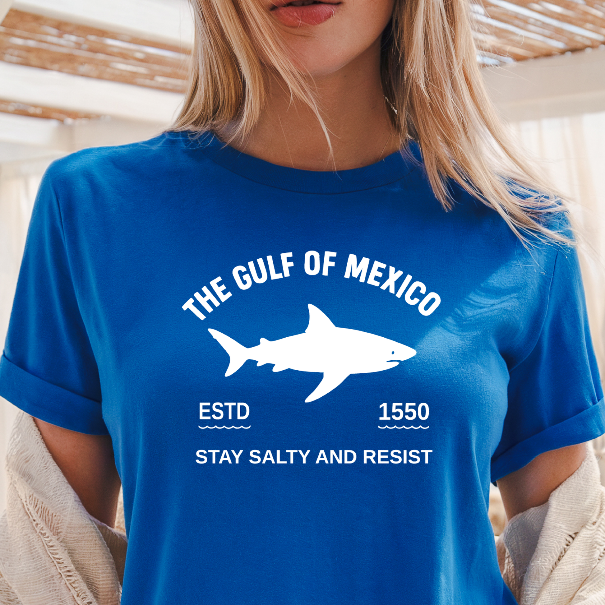Person wearing a royal blue t-shirt with a shark graphic and text about the Gulf of Mexico.
