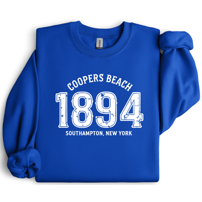Blue sweatshirt with white text 'Coopers Beach 1894 Southampton, New York' on a white background
