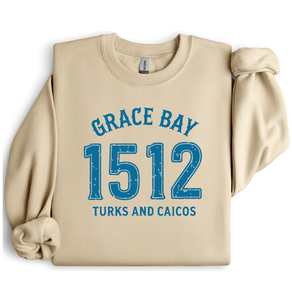 Gildan sweatshirt featuring blue text that reads “Grace Bay 1512 Turks and Caicos” in a vintage collegiate style. Cozy cotton-poly blend pullover with ribbed cuffs and waistband for a relaxed, durable fit. Ideal for beach lovers, island travelers, and fans of coastal fashion. Perfect for staying cozy while showcasing love for one of the Caribbean’s most beautiful beaches — Grace Bay.