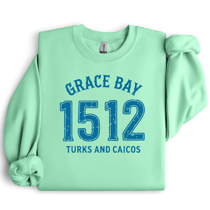 Gildan sweatshirt featuring blue text that reads “Grace Bay 1512 Turks and Caicos” in a vintage collegiate style. Cozy cotton-poly blend pullover with ribbed cuffs and waistband for a relaxed, durable fit. Ideal for beach lovers, island travelers, and fans of coastal fashion. Perfect for staying cozy while showcasing love for one of the Caribbean’s most beautiful beaches — Grace Bay.