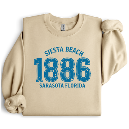 Sand sweatshirt with blue text 'Siesta Beach 1886 Sarasota Florida' on a white background