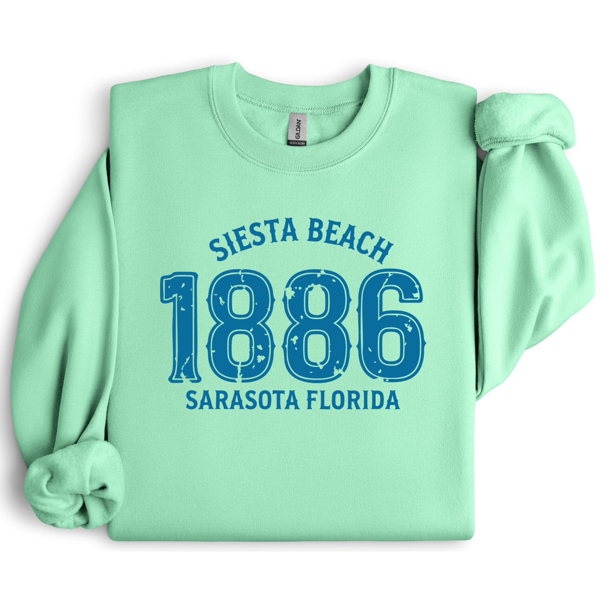Light green sweatshirt with blue text 'Siesta Beach 1886 Sarasota Florida' on a white background