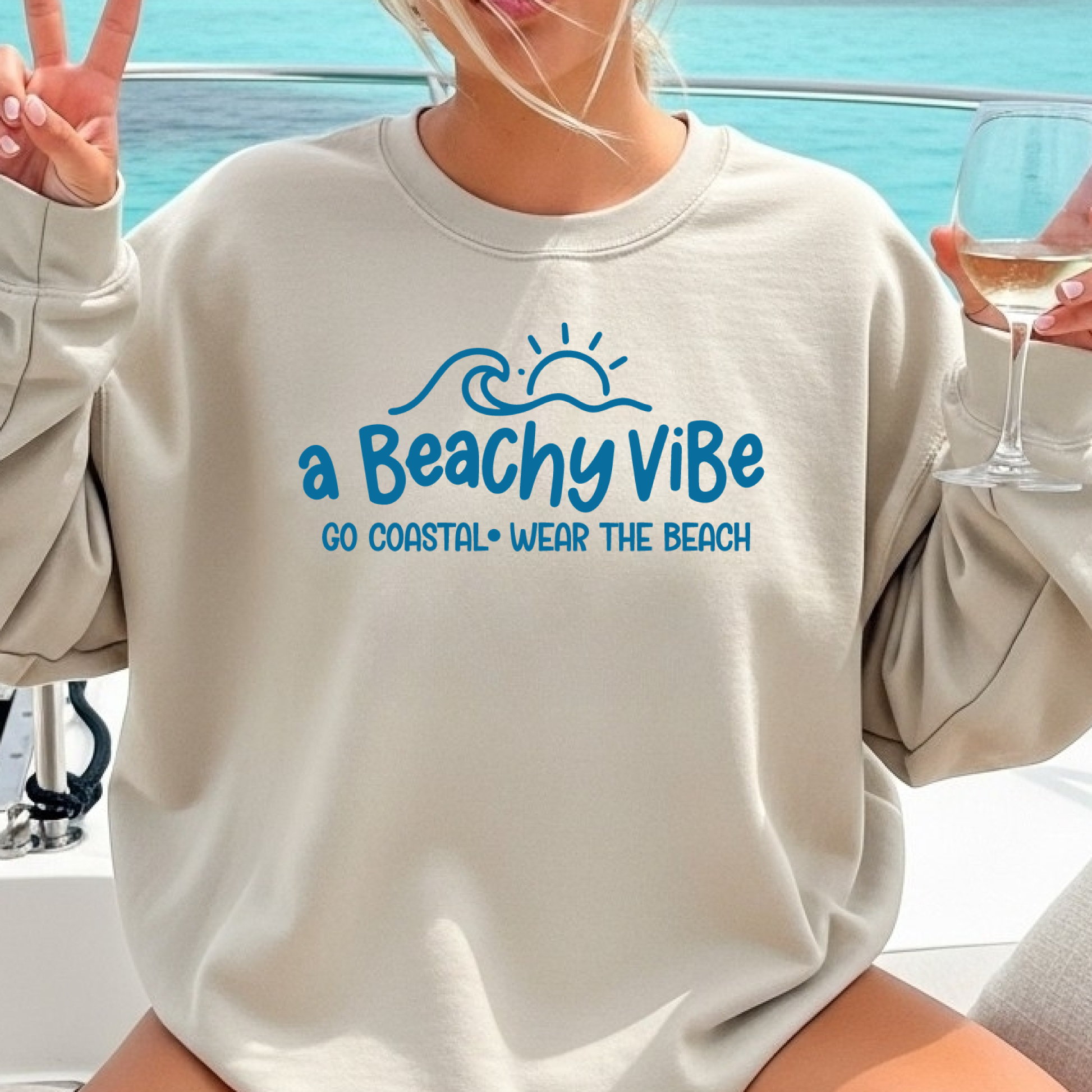 Person wearing a beige sweatshirt with 'a Beachy Vibe' text, sitting on a boat.
