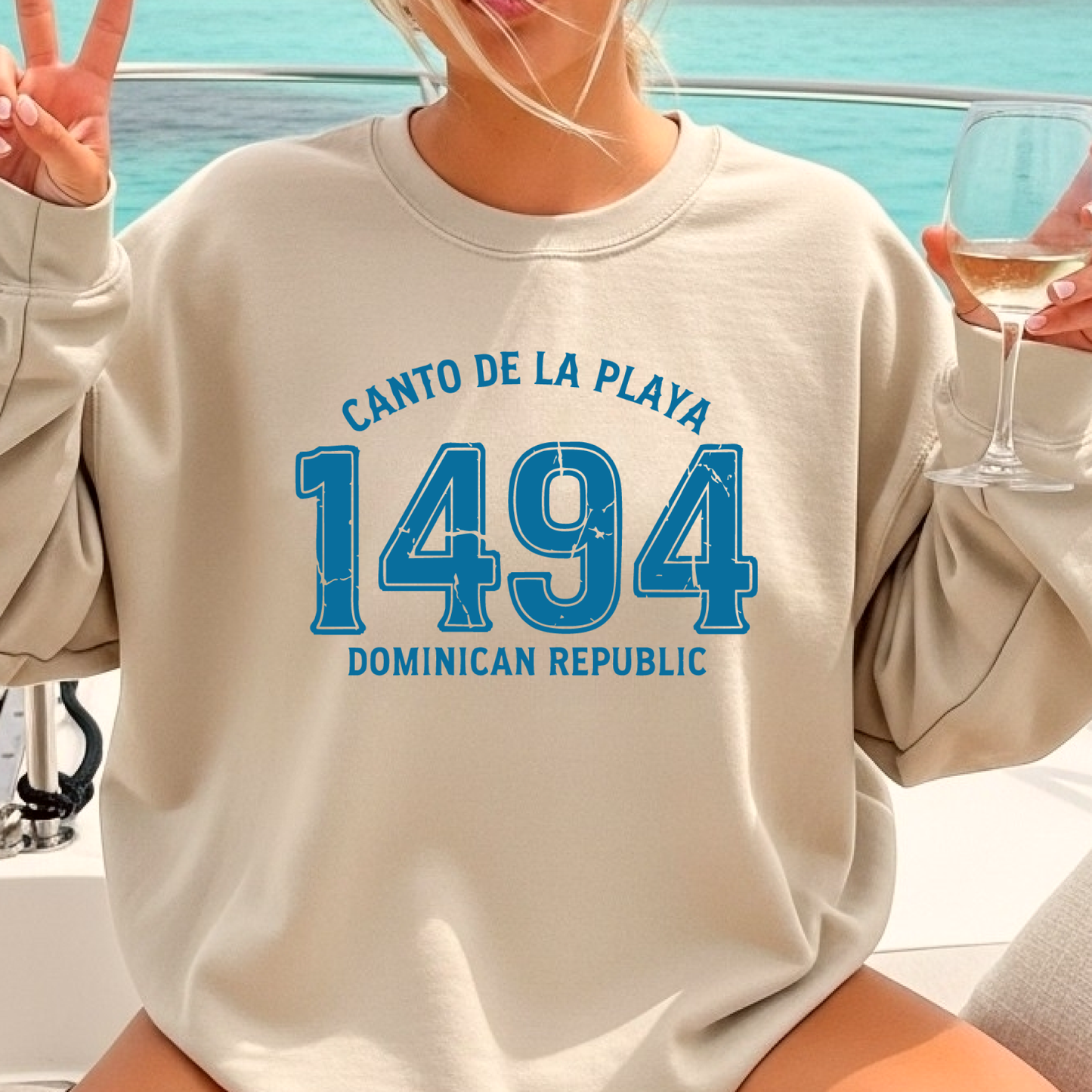 Gildan sweatshirt with “Canto De La Playa 1494 Dominican Republic” printed in distressed navy text. Vintage beach-inspired crewneck symbolizing Caribbean heritage and coastal charm. Made from soft cotton-poly blend fabric for comfort and style, ideal for beach lovers and travelers who adore Dominican culture. Cozy, sustainable, and perfect for casual wear or tropical getaways.