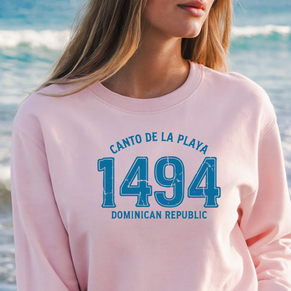 Gildan sweatshirt with “Canto De La Playa 1494 Dominican Republic” printed in distressed navy text. Vintage beach-inspired crewneck symbolizing Caribbean heritage and coastal charm. Made from soft cotton-poly blend fabric for comfort and style, ideal for beach lovers and travelers who adore Dominican culture. Cozy, sustainable, and perfect for casual wear or tropical getaways.