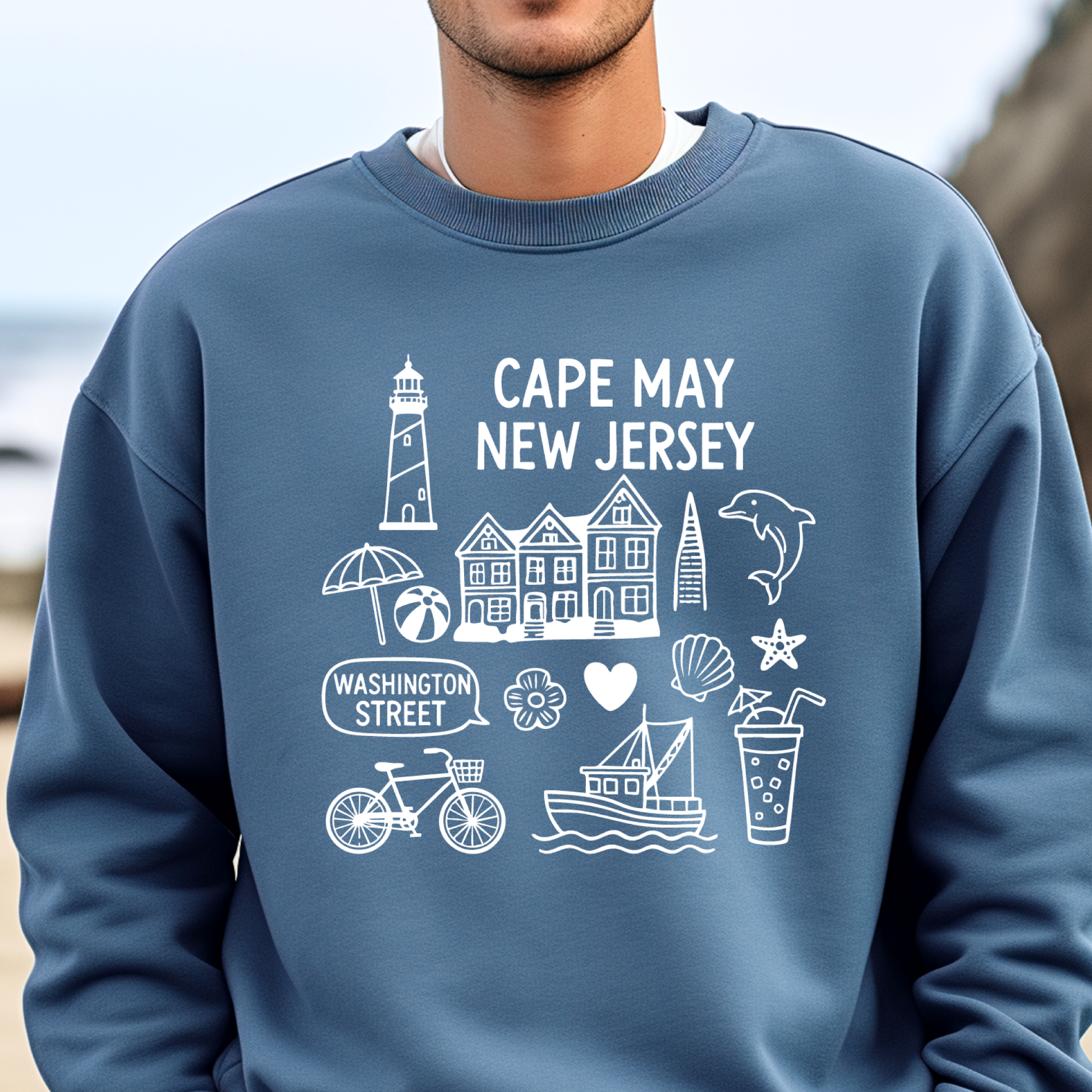 Gildan sweatshirt with blue Cape May New Jersey design featuring beach icons like a lighthouse, dolphin, beach ball, shells, and Washington Street sign. Coastal-inspired pullover made from soft cotton-poly blend fabric, ideal for beach lovers and Cape May fans. Perfect for seaside getaways or relaxing at home, this cozy crewneck celebrates the charm of New Jersey’s iconic coastal town.