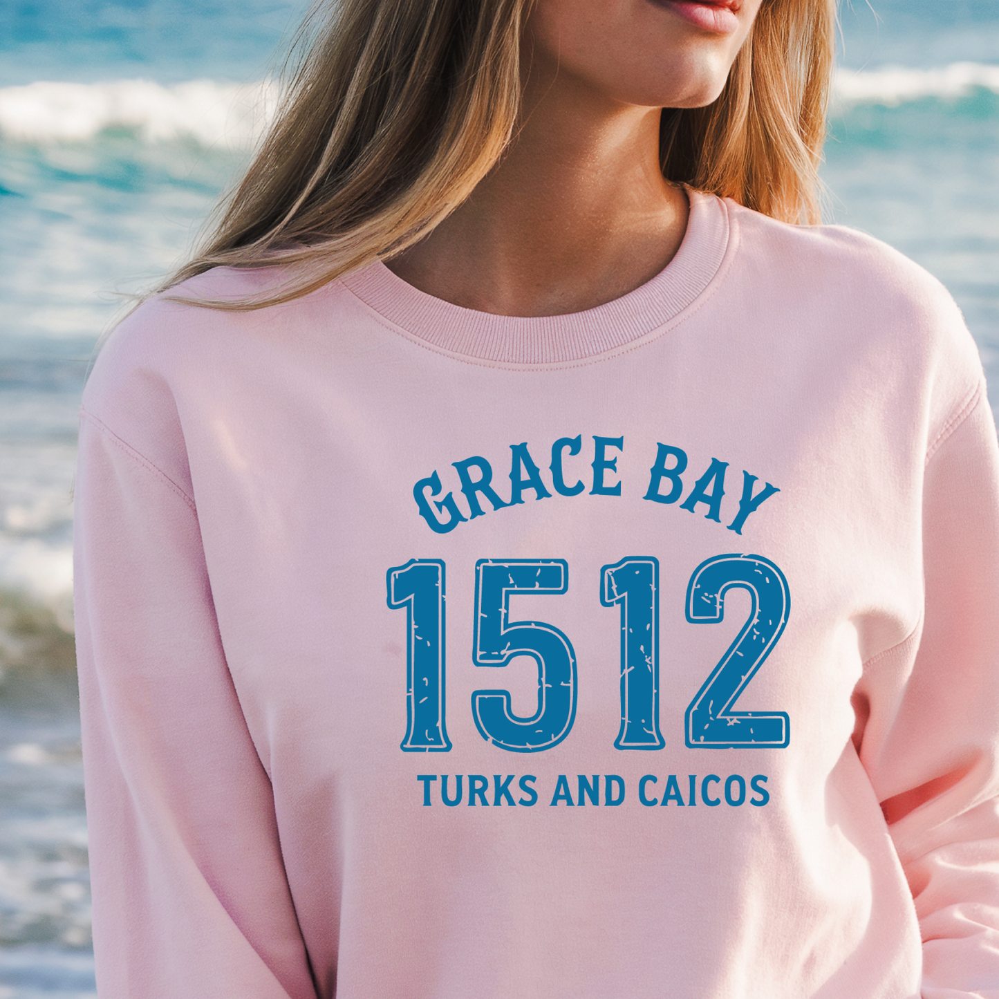 Gildan sweatshirt featuring blue text that reads “Grace Bay 1512 Turks and Caicos” in a vintage collegiate style. Cozy cotton-poly blend pullover with ribbed cuffs and waistband for a relaxed, durable fit. Ideal for beach lovers, island travelers, and fans of coastal fashion. Perfect for staying cozy while showcasing love for one of the Caribbean’s most beautiful beaches — Grace Bay.