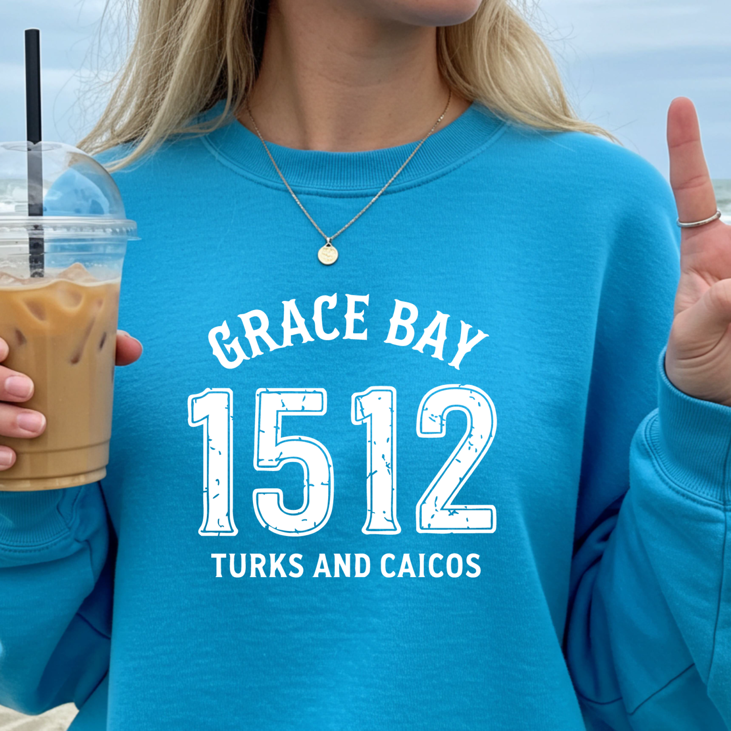 Gildan sweatshirt featuring blue text that reads “Grace Bay 1512 Turks and Caicos” in a vintage collegiate style. Cozy cotton-poly blend pullover with ribbed cuffs and waistband for a relaxed, durable fit. Ideal for beach lovers, island travelers, and fans of coastal fashion. Perfect for staying cozy while showcasing love for one of the Caribbean’s most beautiful beaches — Grace Bay.