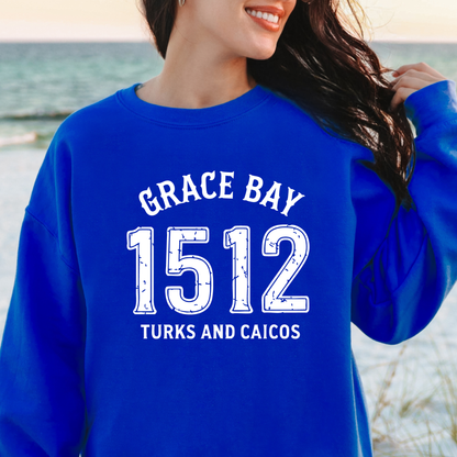 Gildan sweatshirt featuring blue text that reads “Grace Bay 1512 Turks and Caicos” in a vintage collegiate style. Cozy cotton-poly blend pullover with ribbed cuffs and waistband for a relaxed, durable fit. Ideal for beach lovers, island travelers, and fans of coastal fashion. Perfect for staying cozy while showcasing love for one of the Caribbean’s most beautiful beaches — Grace Bay.