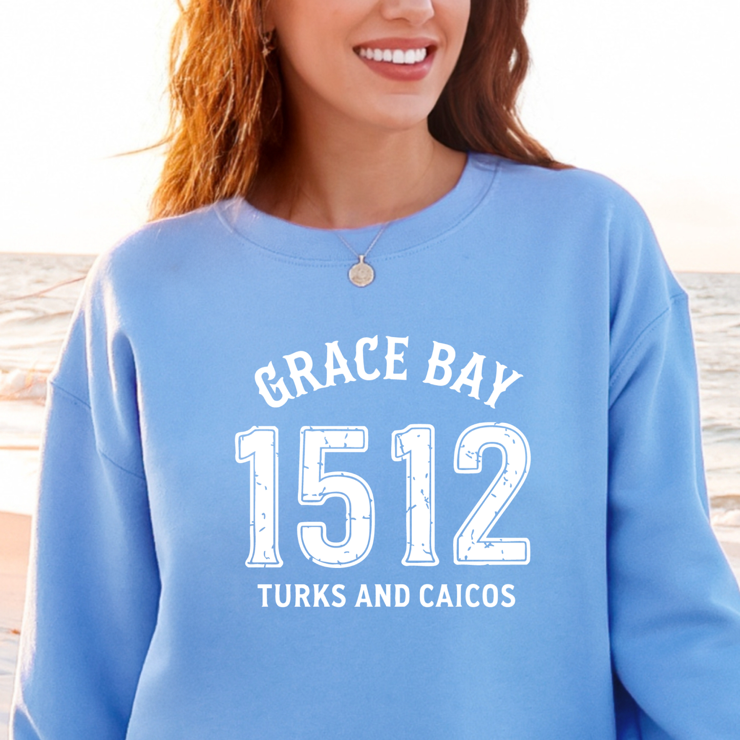 Gildan sweatshirt featuring blue text that reads “Grace Bay 1512 Turks and Caicos” in a vintage collegiate style. Cozy cotton-poly blend pullover with ribbed cuffs and waistband for a relaxed, durable fit. Ideal for beach lovers, island travelers, and fans of coastal fashion. Perfect for staying cozy while showcasing love for one of the Caribbean’s most beautiful beaches — Grace Bay.