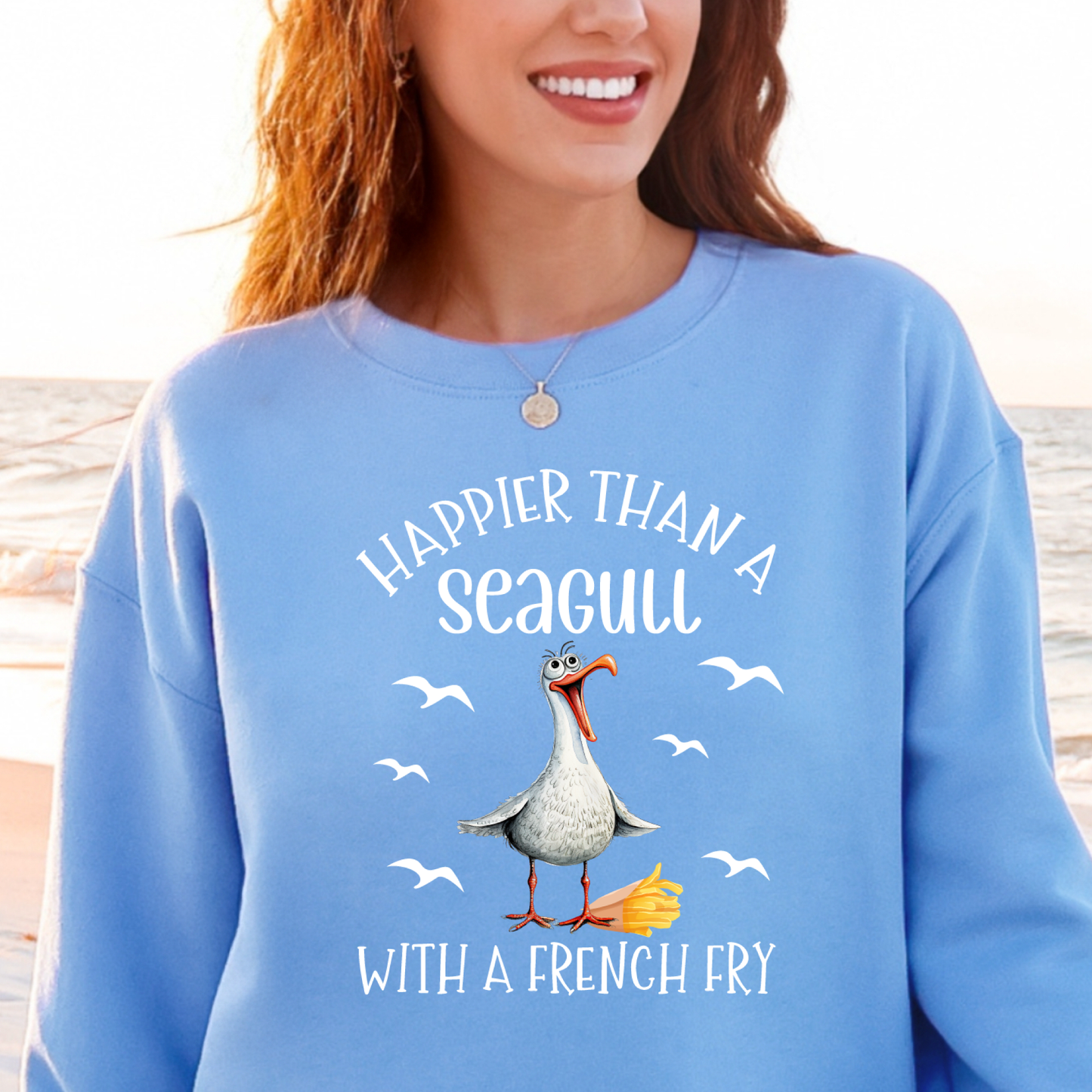 Person wearing a Carolina blue sweatshirt with a seagull graphic and text at a beach.