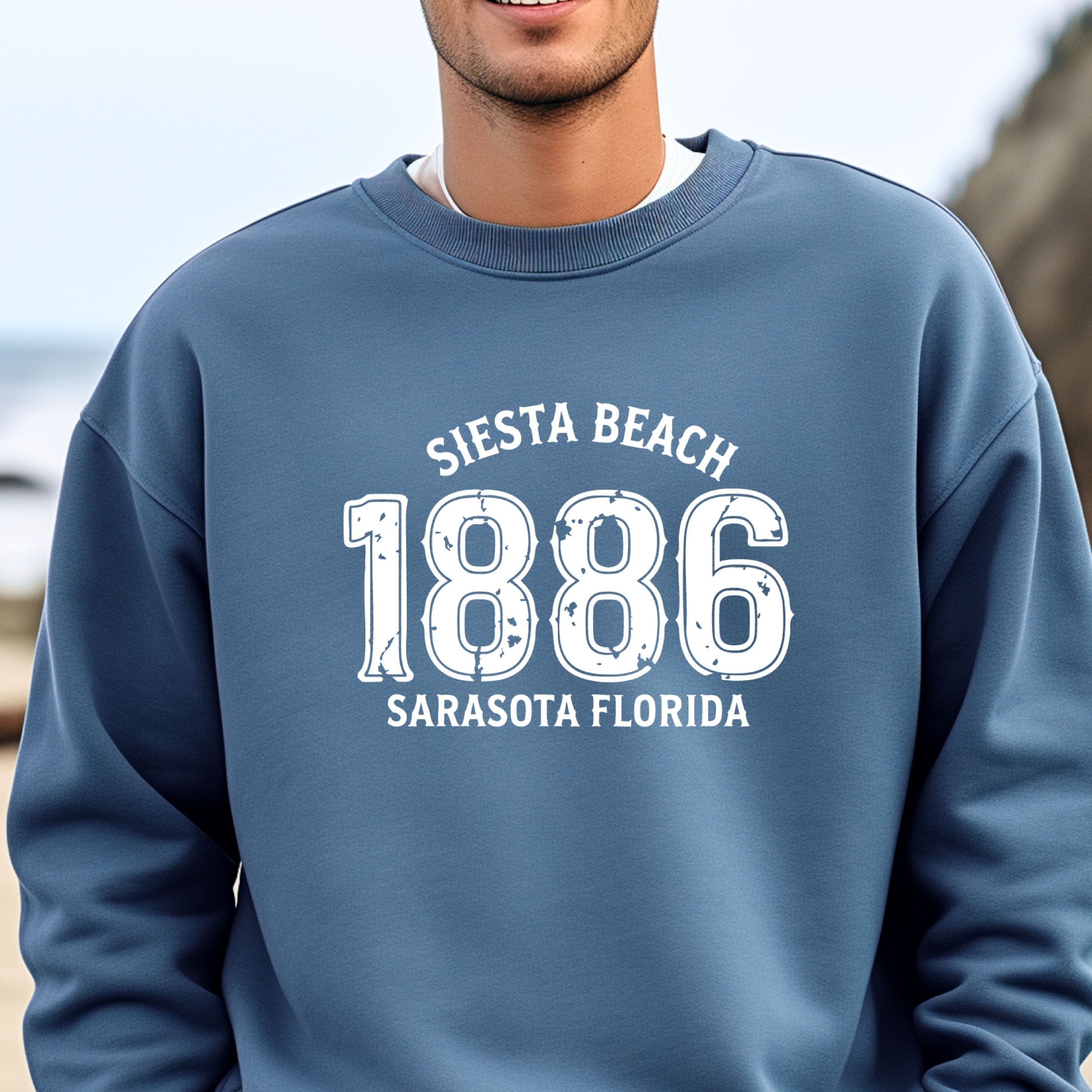 Person wearing a indigo blue sweatshirt with 'Siesta Beach 1886 Sarasota Florida' text.