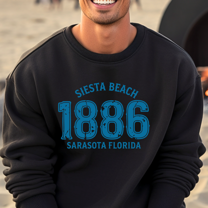 Person wearing a black sweatshirt with blue text 'Siesta Beach 1886 Sarasota Florida' on a beach.