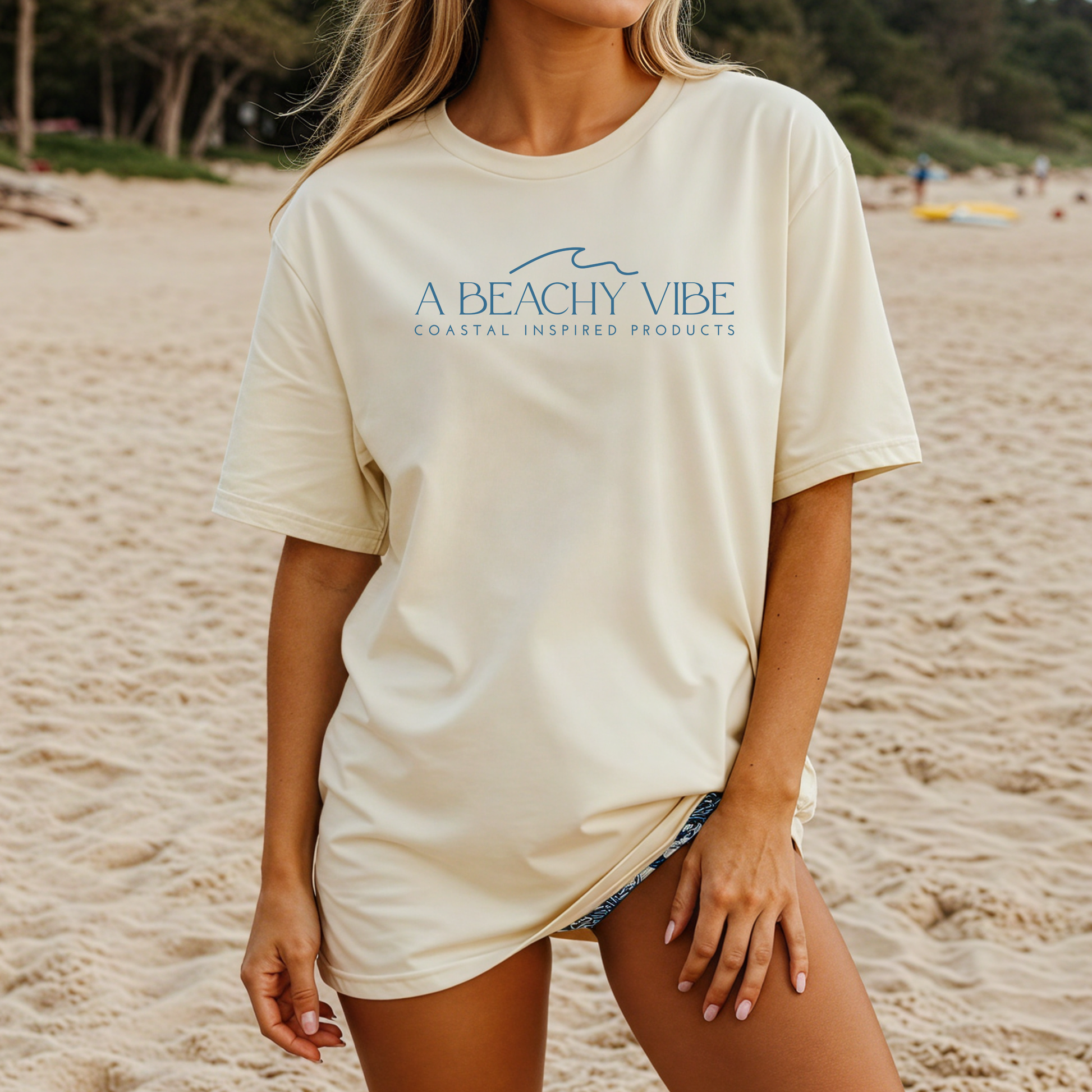 Comfort Colors 1717 "A Beachy Vibe" t shirt with a simple wave one color graphic. Picture of a girl standing on the beach in an oversized t shirt.